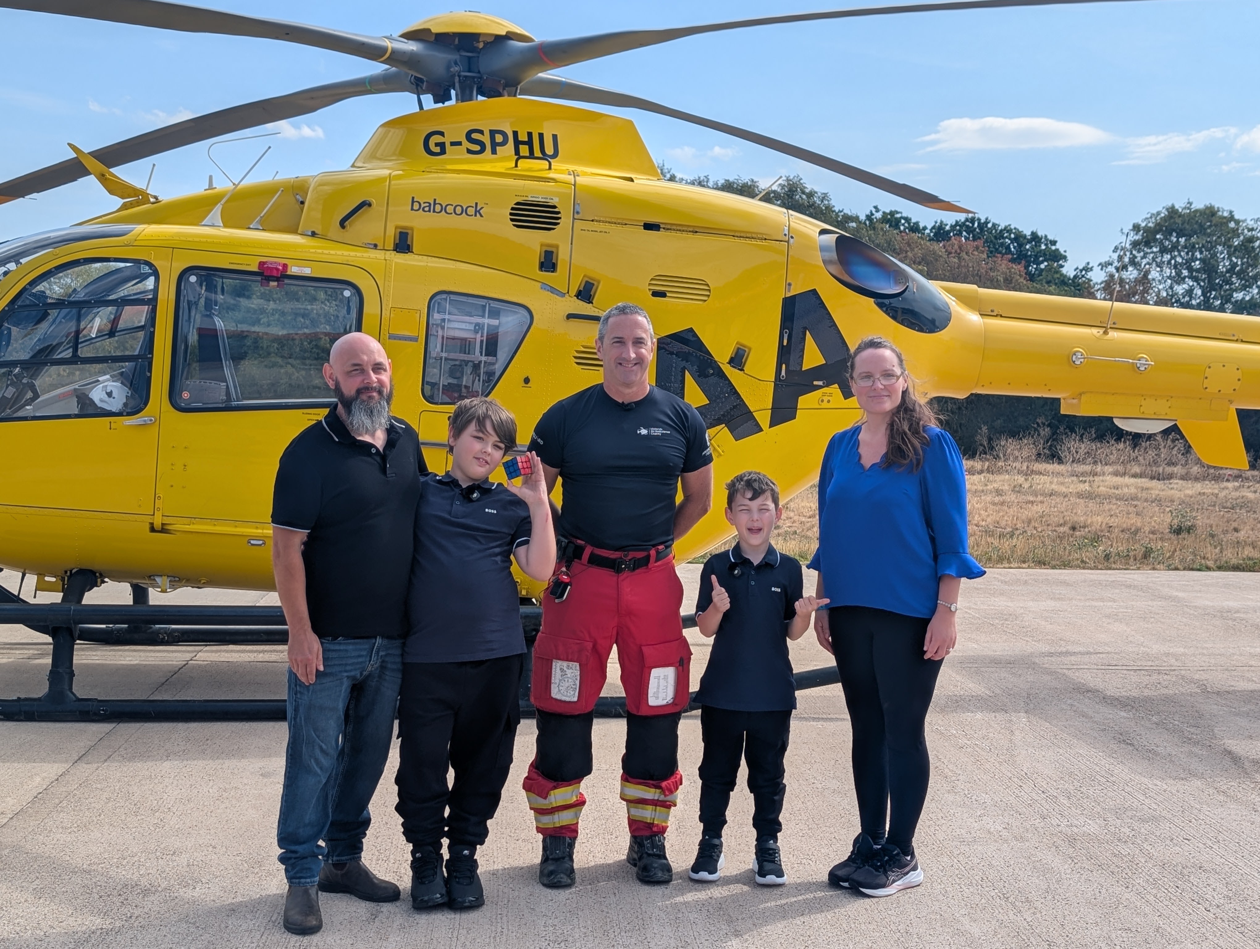 George and Alfie with family members and an air ambulance crew member in front of a helicopter at Strensham airbase