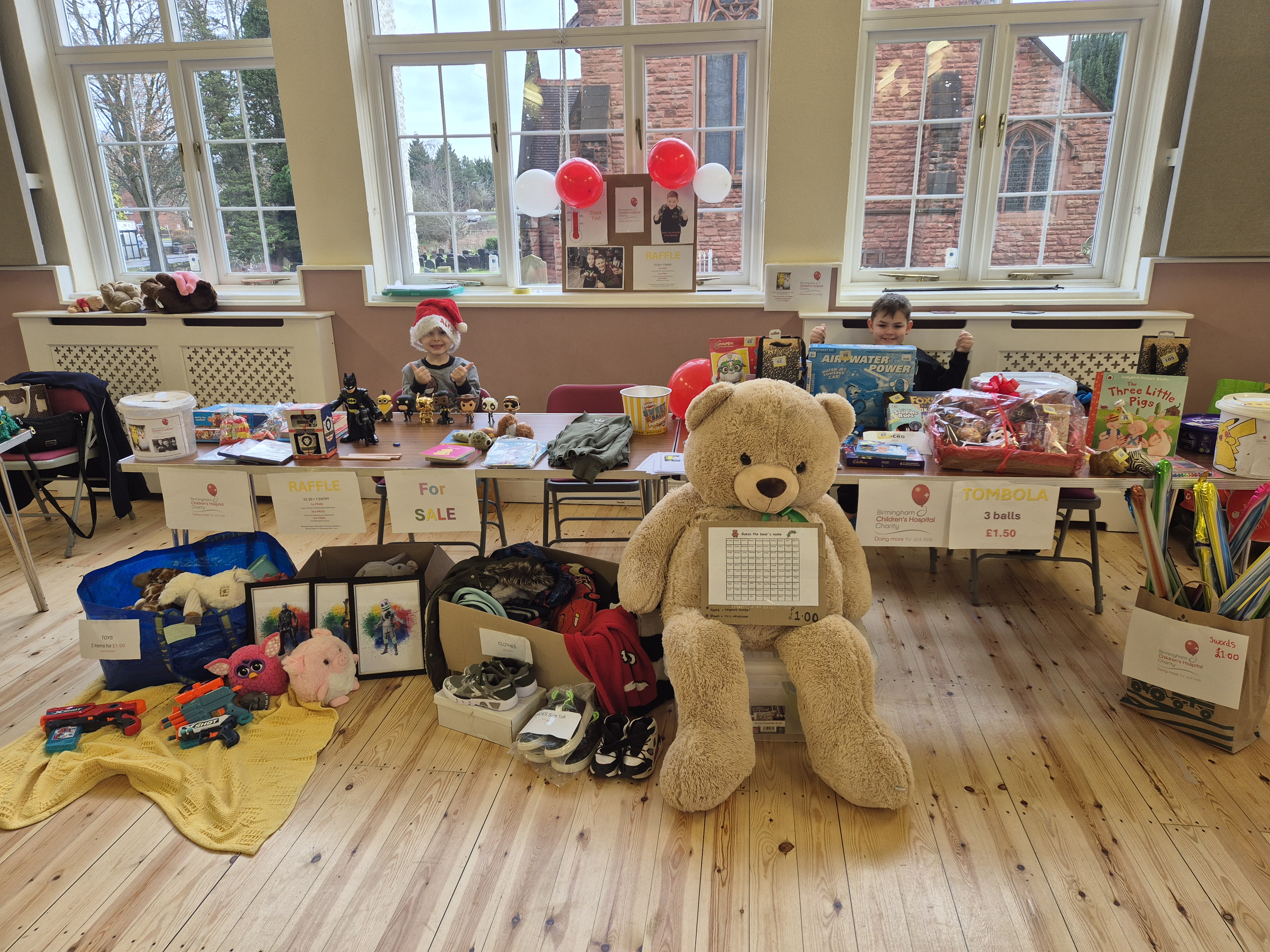 George and Alfie behind a community raffle and tombola stall